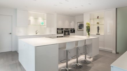 White kitchen with central island and integrated appliances in a modern design.
