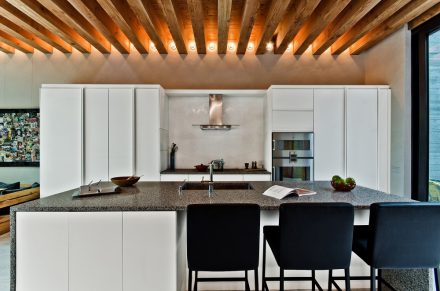 Kitchen with dark worktop, white cabinets and modern lighting.