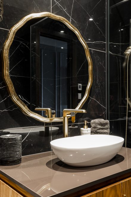 Dark bathroom with a mirror and a golden faucet.